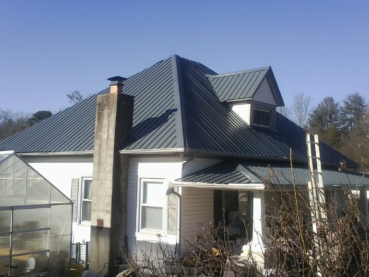 Dark blue standing seam metal roof on a white farmhouse with dormer — Slate & Tile Roof Repair by Roofing Brothers in Forest Ranch
