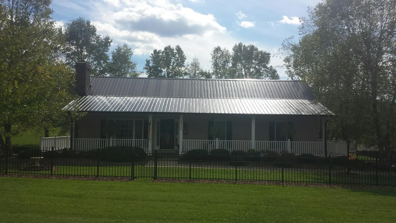 Gray metal roof on a brick ranch with a full width front porch — Gutter Guard Installation work by our crew in Forest Ranch