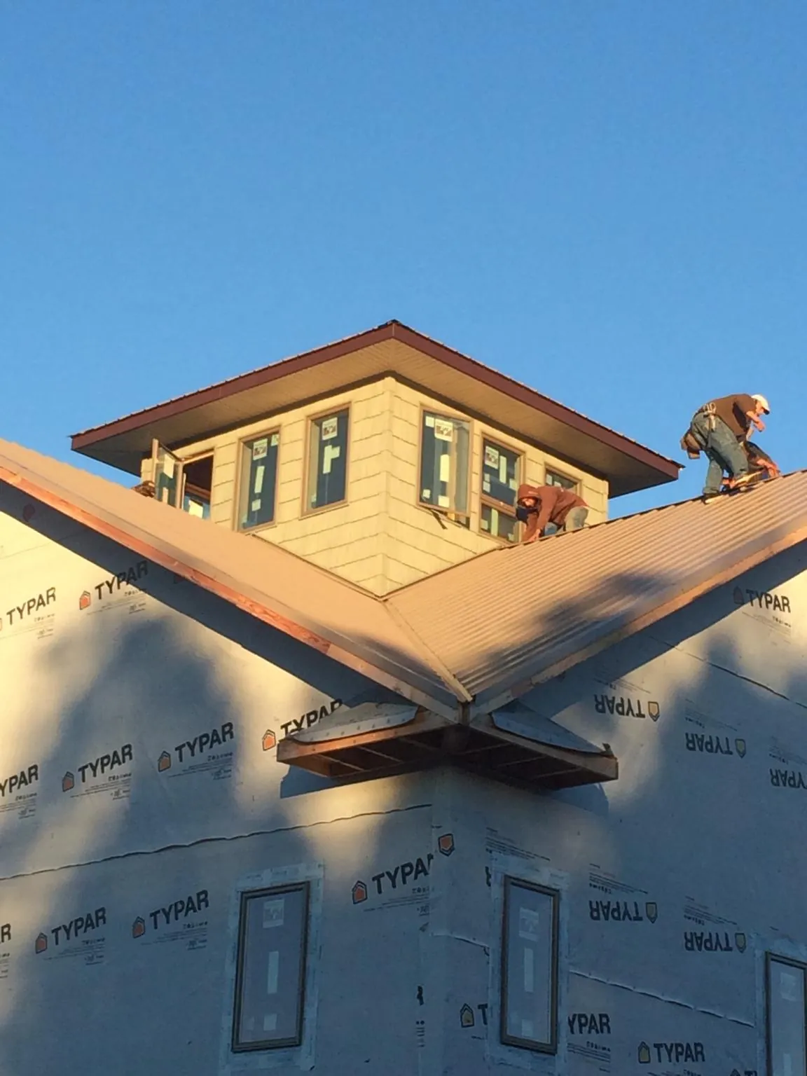 Roofers working around a rooftop cupola on a new metal roof at sunset — Roof Waterproofing in Forest Ranch by Roofing Brothers